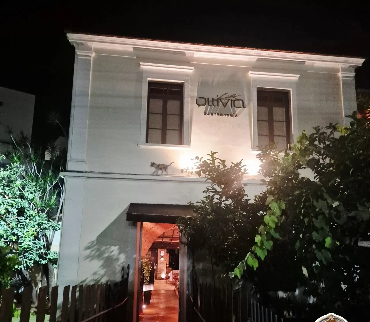 Fachada do casarão branco do Ollivia Gastronomia iluminada à noite, em Poços de Caldas